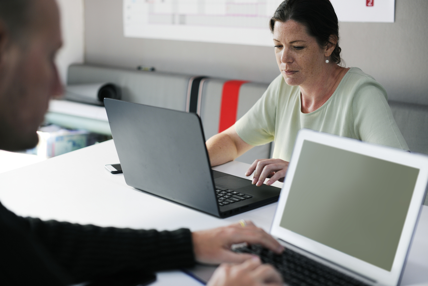 Woman working on a desk writing on the keyboard of a laptop