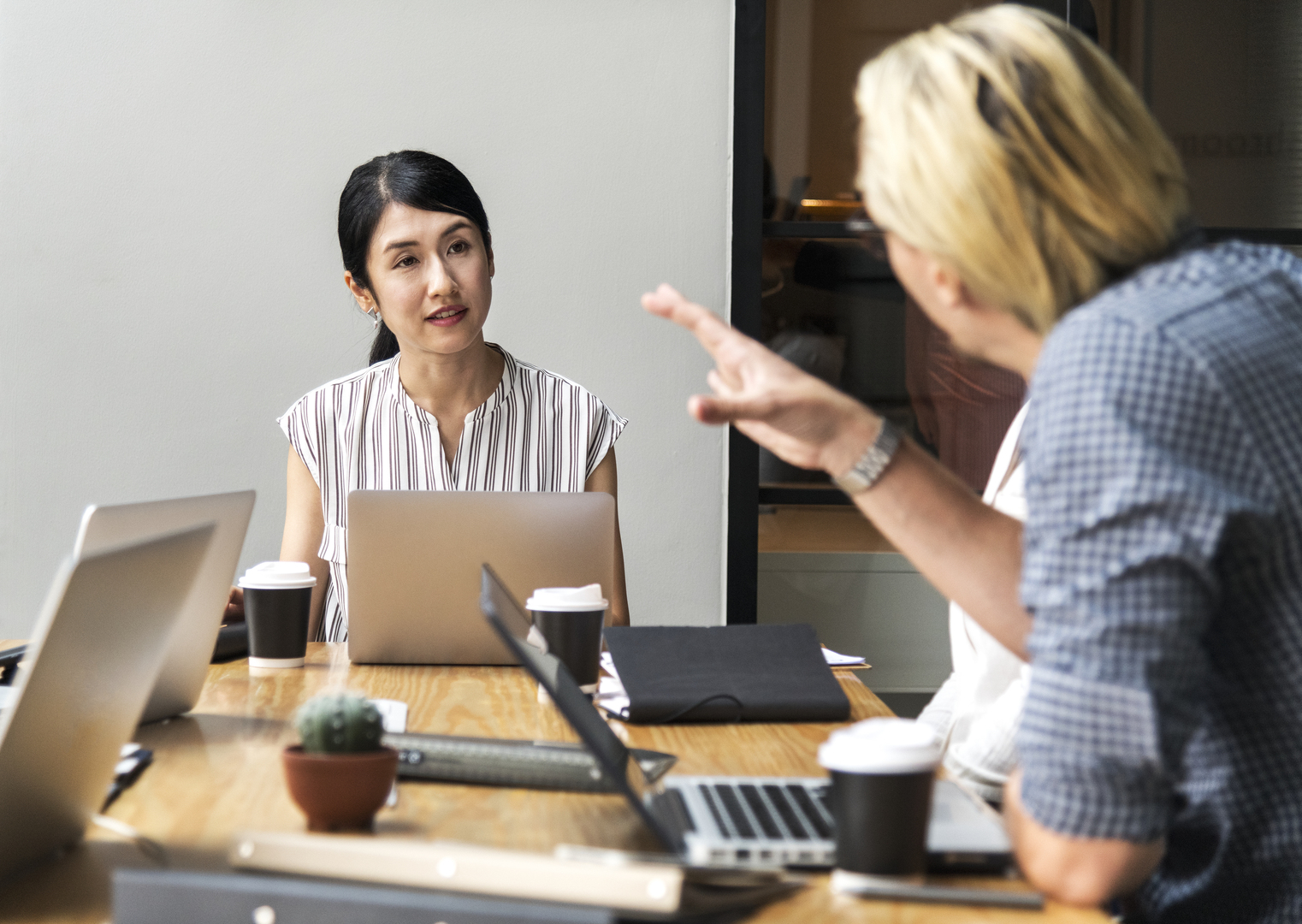 a woman and a man discussing in a meeting sitting on a big table